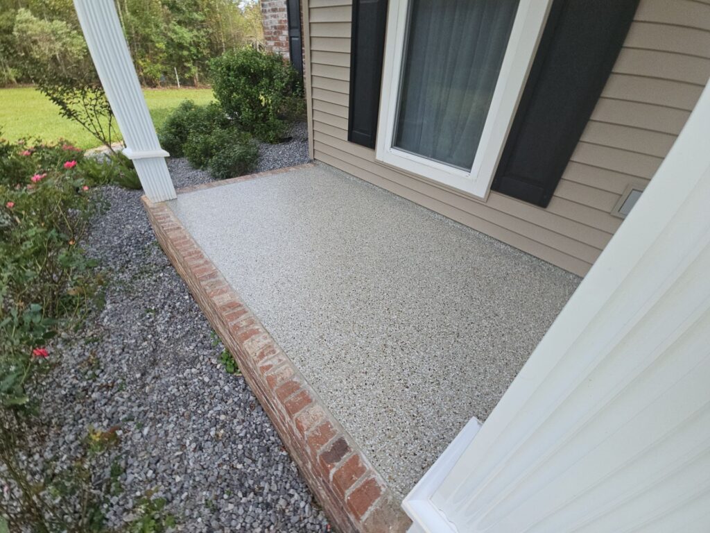A beautiful, glossy gray polyurea-coated patio with stylish outdoor furniture and green plants.
