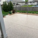 A pristine, gray coated patio with modern outdoor furniture, showcasing the benefits of regular maintenance.